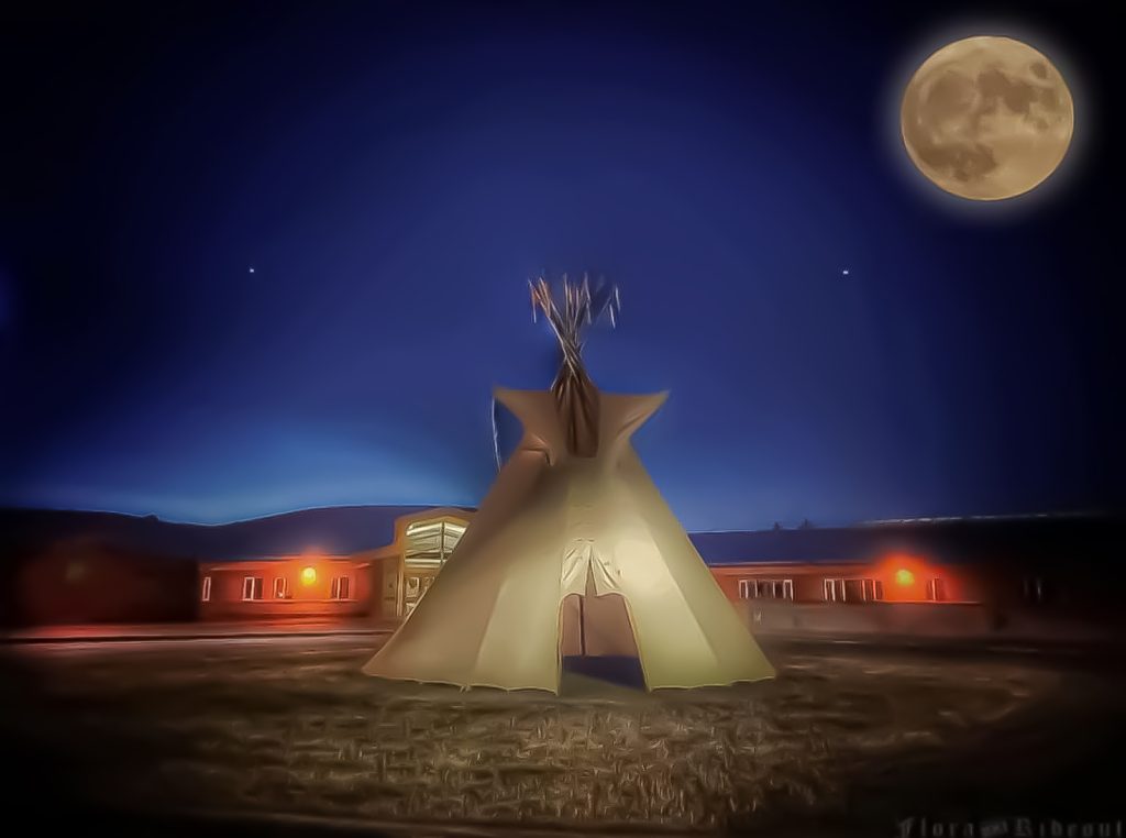 image of tipi at dusk in front of a school