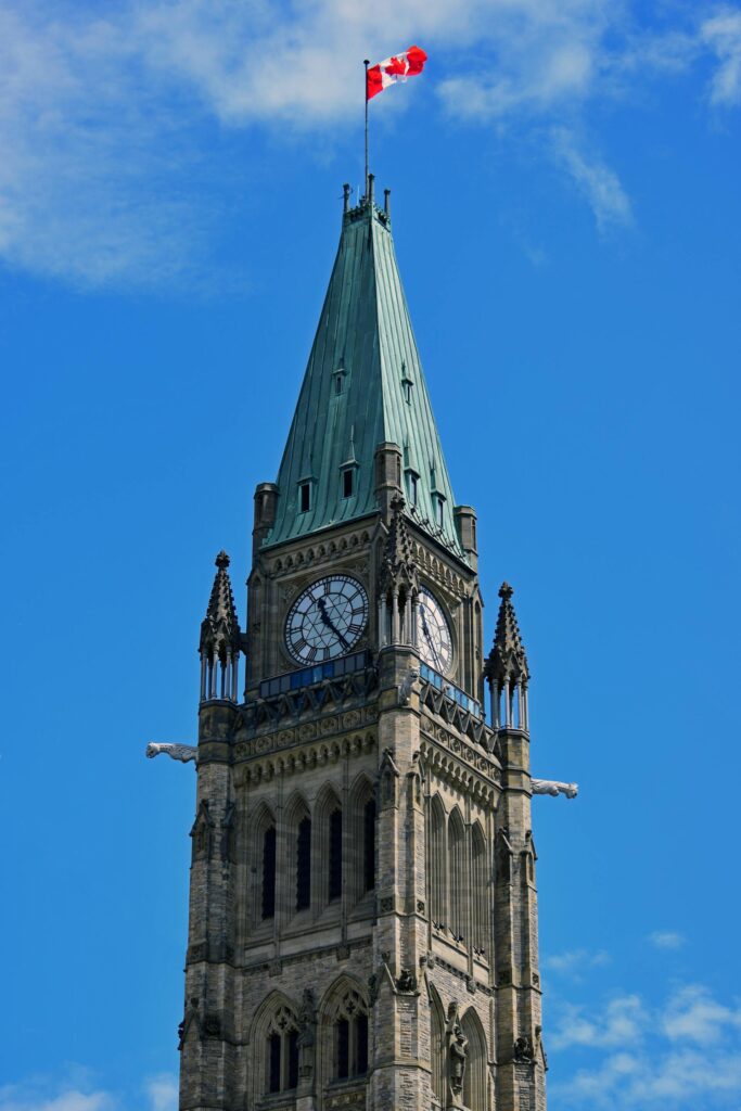 clocktower flying a canadian flag - Photo by Deneen L Treble: https://www.pexels.com/photo/low-angle-shot-of-a-clock-tower-under-the-blue-sky-12845535/